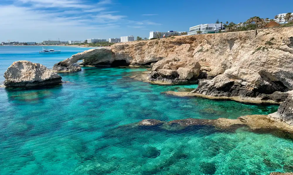 A vibrant and clear photograph showcasing the clear turquoise waters and rocky coastline of Ayia Napa, ideal for summer activities like snorkeling and cliff diving.