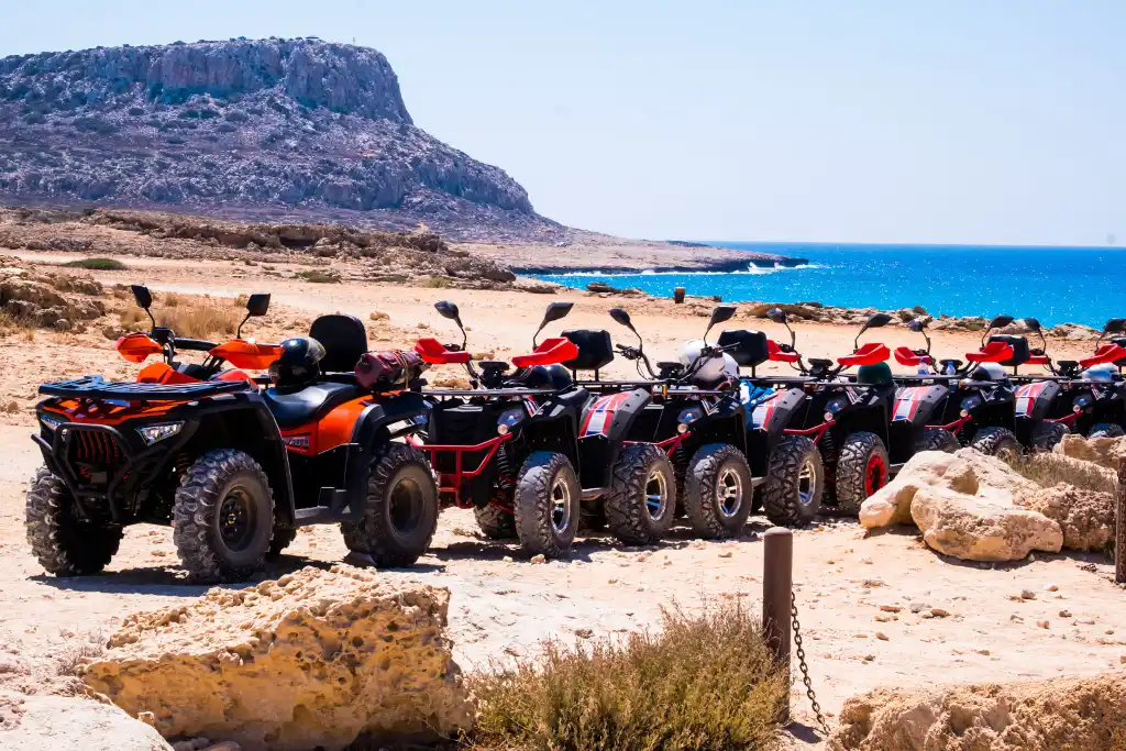 A lineup of quad bikes on the desert terrain of Cape Greco, Ayia Napa, Cyprus, with the Mediterranean Sea in the background.