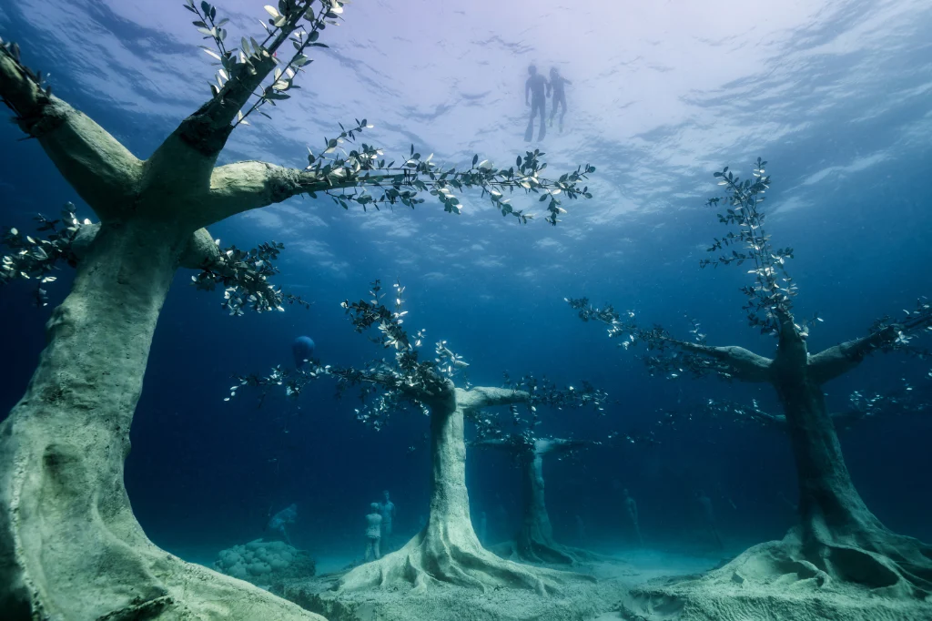 Underwater view of the sculpture park at MUSAN with snorkelers exploring in the background in the clear waters of Cyprus