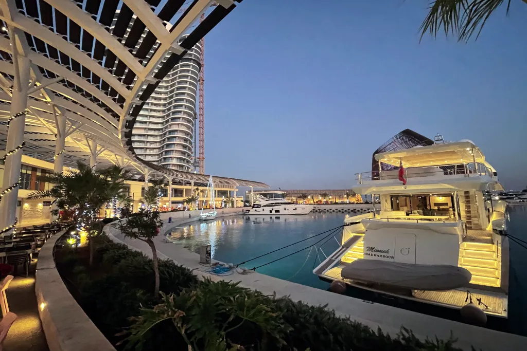 Luxurious yacht docked at the Ayia Napa Marina in Cyprus during twilight, with modern architecture and calm waters.