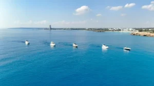 A serene fleet of yachts cruising the azure waters of Ayia Napa with the developing skyline in the backdrop.