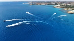 Yachts speeding through the sea near Ayia Napa, creating dynamic patterns on the water's surface with the coastline in the distance.