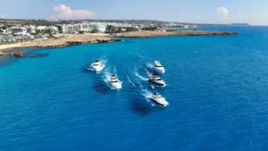 Aerial view of a group of boats cruising along the beautiful blue waters off the coast of Ayia Napa with resorts in the background.