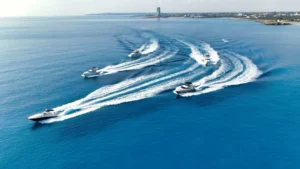 Aerial view of boats cruising on the blue waters near Ayia Napa, leaving white wake patterns, with the coast in the background.