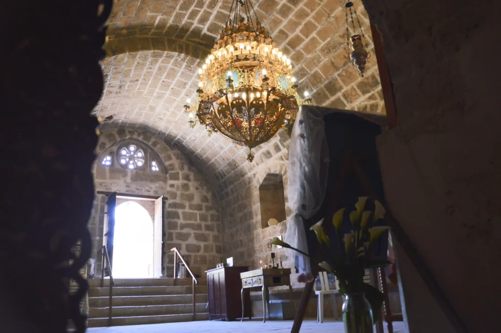 Interior of Ayia Napa Monastery with a chandelier, stone walls, and arched ceilings.