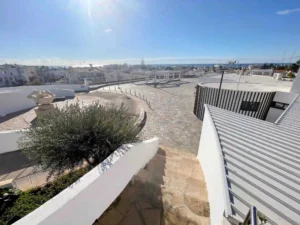 Spacious terrace in Ayia Napa near our featuring properties, with stone flooring, white railings, and a scenic view of the town and sea.