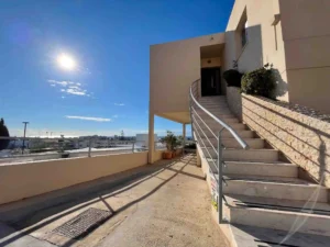 Sunny terrace with a sweeping staircase leading to a residence in Ayia Napa, set against a clear blue sky.