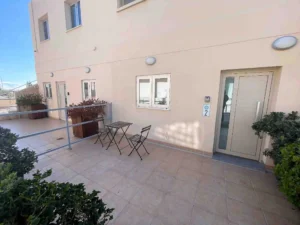 Private terrace with seating outside an apartment in Ayia Napa, surrounded by plants and bathed in sunlight.