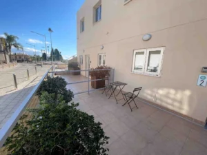 A sunlit terrace with a simple bistro table and chairs outside an apartment in Ayia Napa, capturing a relaxed outdoor living atmosphere.