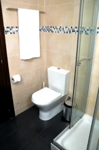 Contemporary bathroom with beige and mosaic tiles, walk-in shower, and white sanitary fixtures in Ayia Napa accommodation.