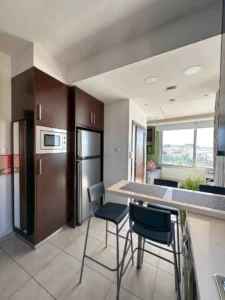 Modern kitchen with island and high stools, offering views of Ayia Napa Bay in Cyprus through large windows