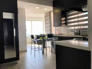 Spacious open-plan kitchen with a central island, leading to a dining area with natural light and views of Ayia Napa Bay, Cyprus.