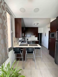 Fully equipped kitchen with island seating in Ayia Napa accommodation, featuring a view of the bay and proximity to local amenities.