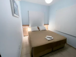 Minimalist bedroom with soft blue walls, a large comfortable bed, and simple decor, promising a peaceful night's sleep in Ayia Napa.