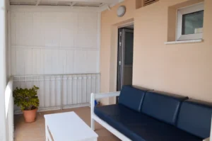 Enclosed balcony with a navy-blue sofa and white coffee table, offering a cozy space to relax outside an Ayia Napa apartment.