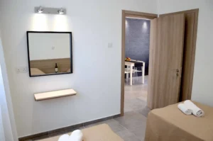 Modern bedroom with a view through the doorway to the dining area, featuring neutral tones and a simple, elegant design in an Ayia Napa apartment.