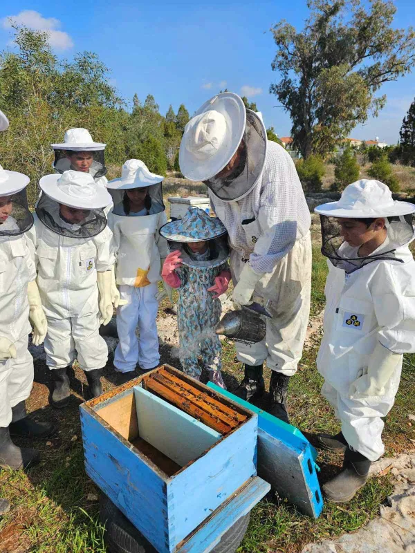 Beekeeping experience with a family wearing protective suits learning about honey production at Topikos Apartments' educational tour in Ayia Napa, Cyprus.