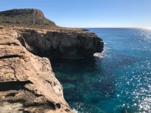 The rugged cliffs of Cape Greco overlooking the clear blue Mediterranean Sea.