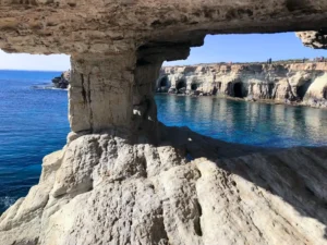 The natural stone bridge and sea caves at Cape Greco, near Topikos Apartments in Ayia Napa, Cyprus, against a backdrop of clear blue waters.