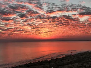 Breathtaking sunset at Cape Greco with vibrant orange and pink clouds reflected in the calm Mediterranean Sea, viewed from Topikos Apartments in Ayia Napa