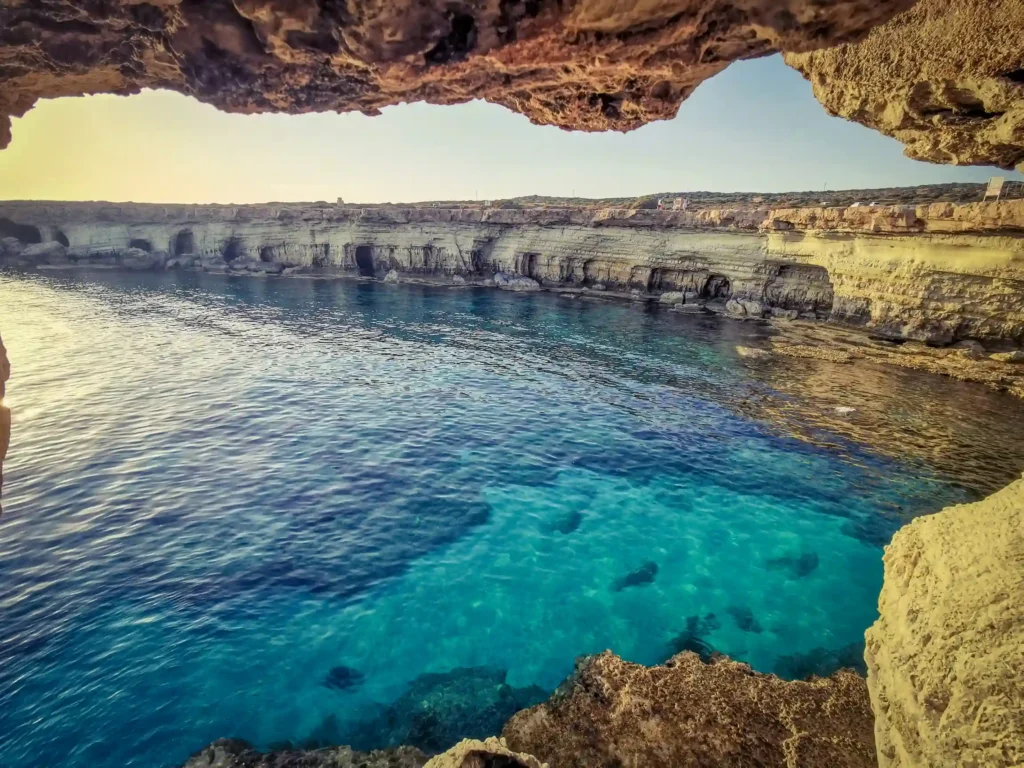 View of the vibrant blue sea through the natural arch of the sea caves at Cape Greco.