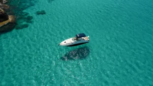 A solitary yacht anchored in clear turquoise waters under a bright sun.