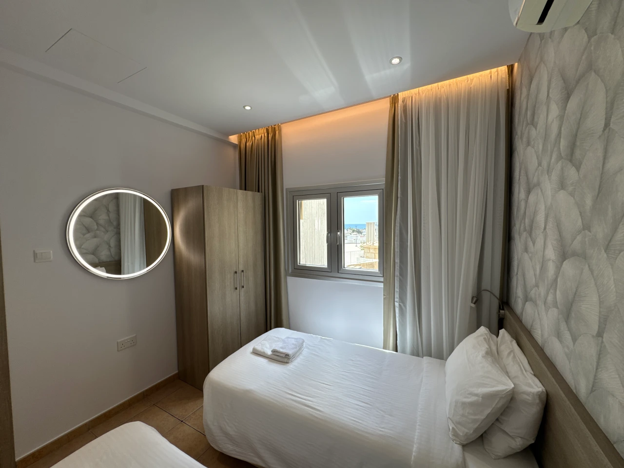 Bright twin bedroom with two single beds and a window in the Central Charming Apartment with Balcony Sea View, Ayia Napa, Cyprus.