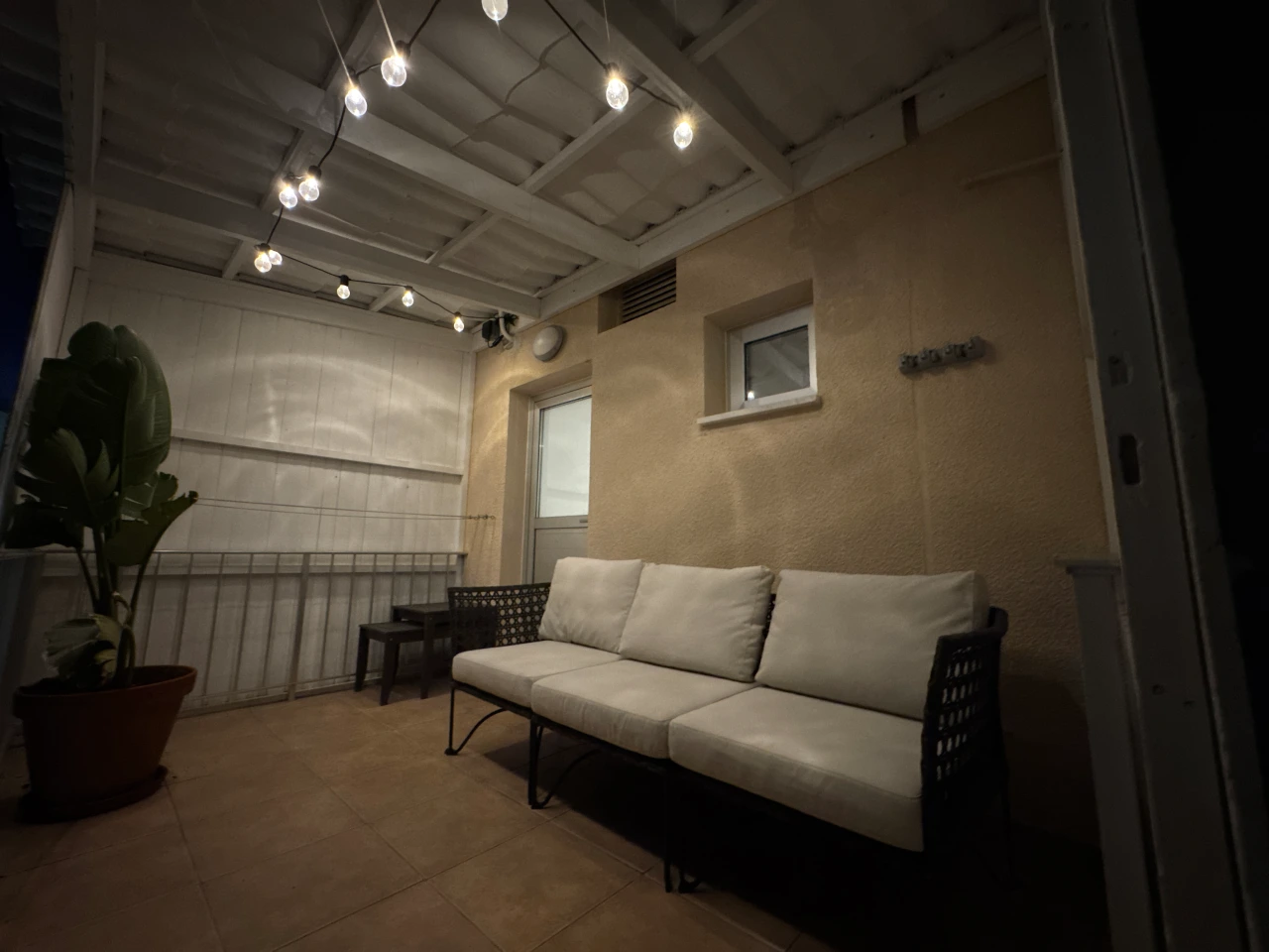 Balcony with a comfortable sofa and string lights at night in the Charming Central Apartment with Sea View Balcony, Ayia Napa, Cyprus.