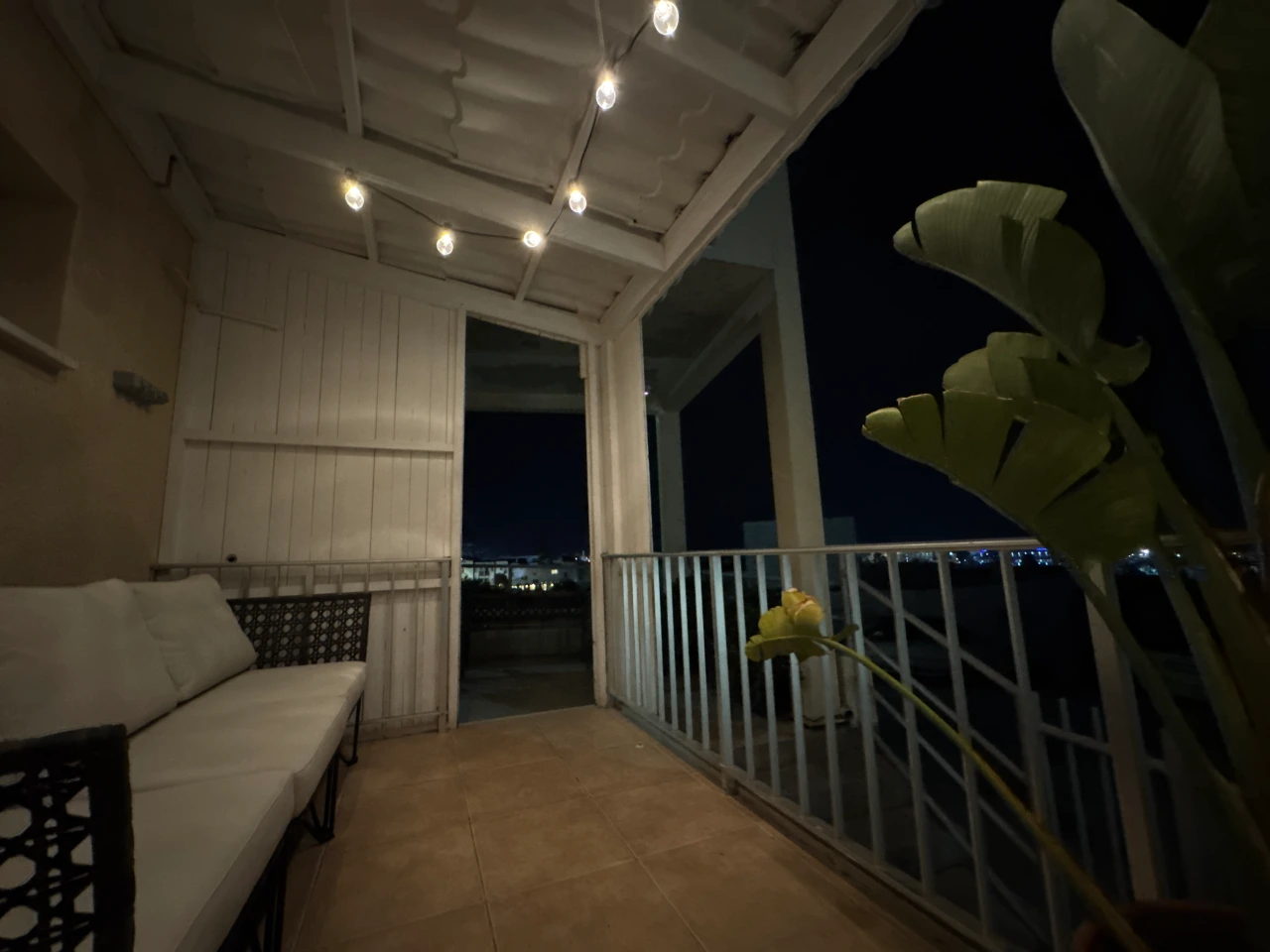 Balcony with a sofa, string lights, and a view of the night sky in the Charming Central Apartment with Sea View Balcony, Ayia Napa, Cyprus.