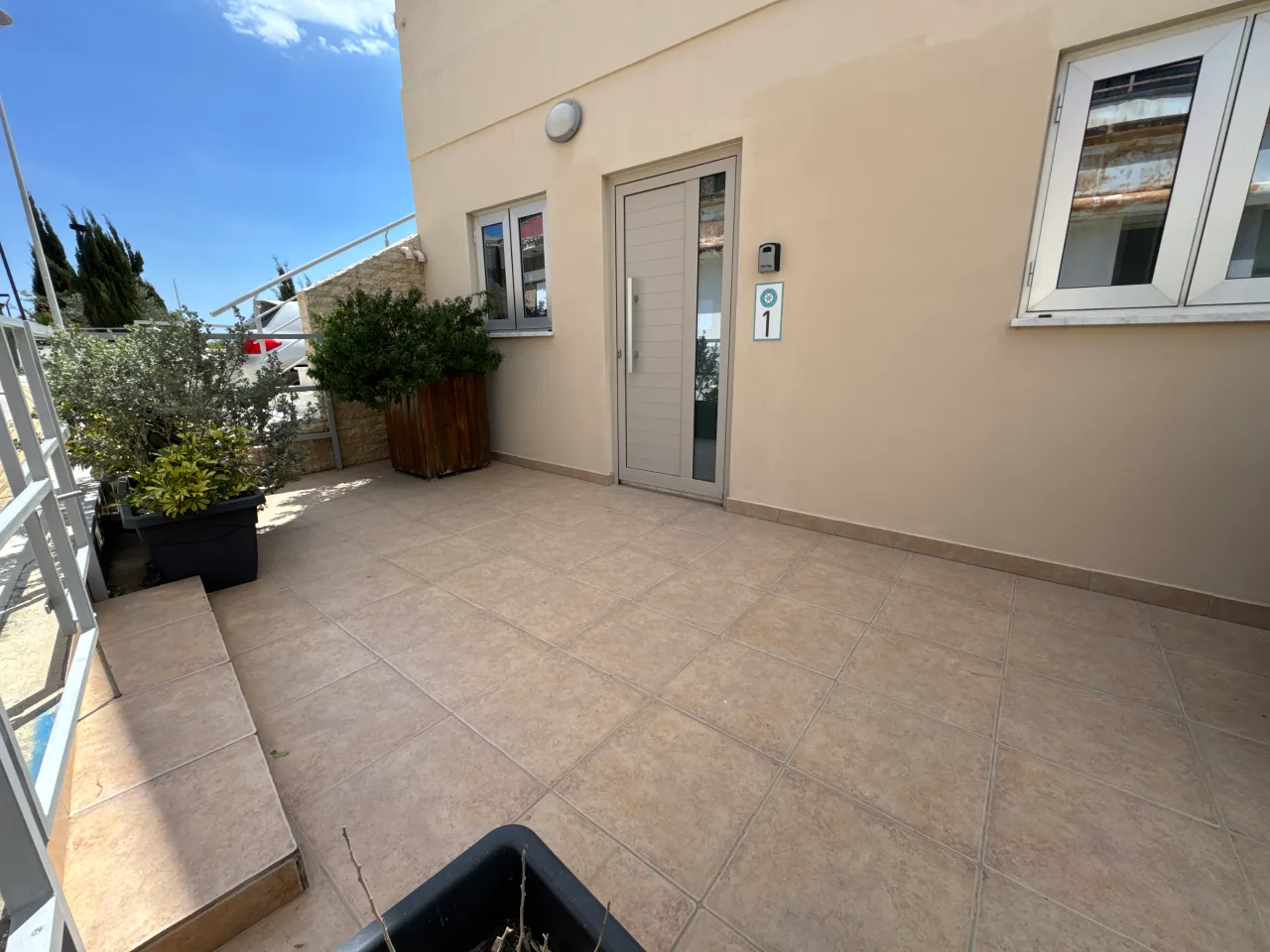 Entrance area with a door and plants at the Charming Central Apartment with Sea View Balcony, Ayia Napa, Cyprus.